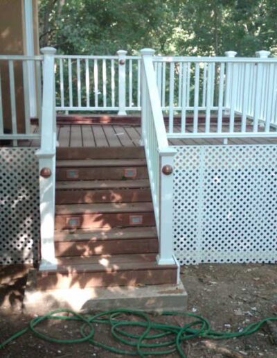 A deck with stairs and a white railing.