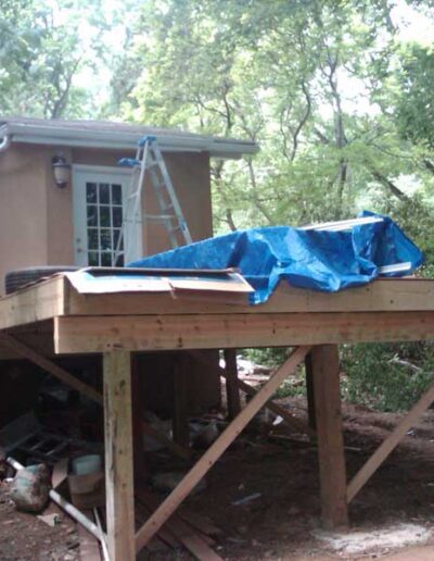 A wooden deck with a blue tarp covering it.