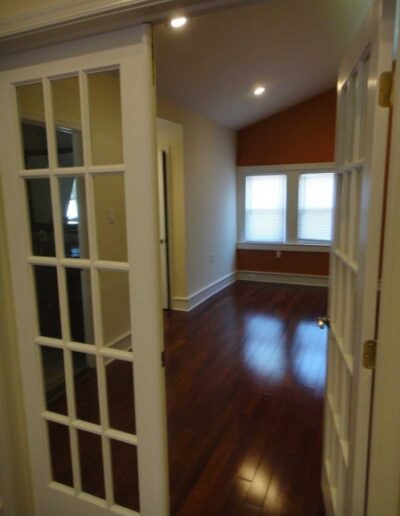 A living room with white doors and hardwood floors.