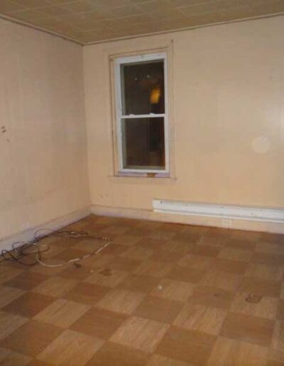 An empty room with a checkered floor and a window.