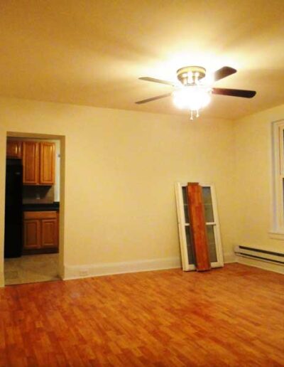 An empty room with hardwood floors and a ceiling fan.